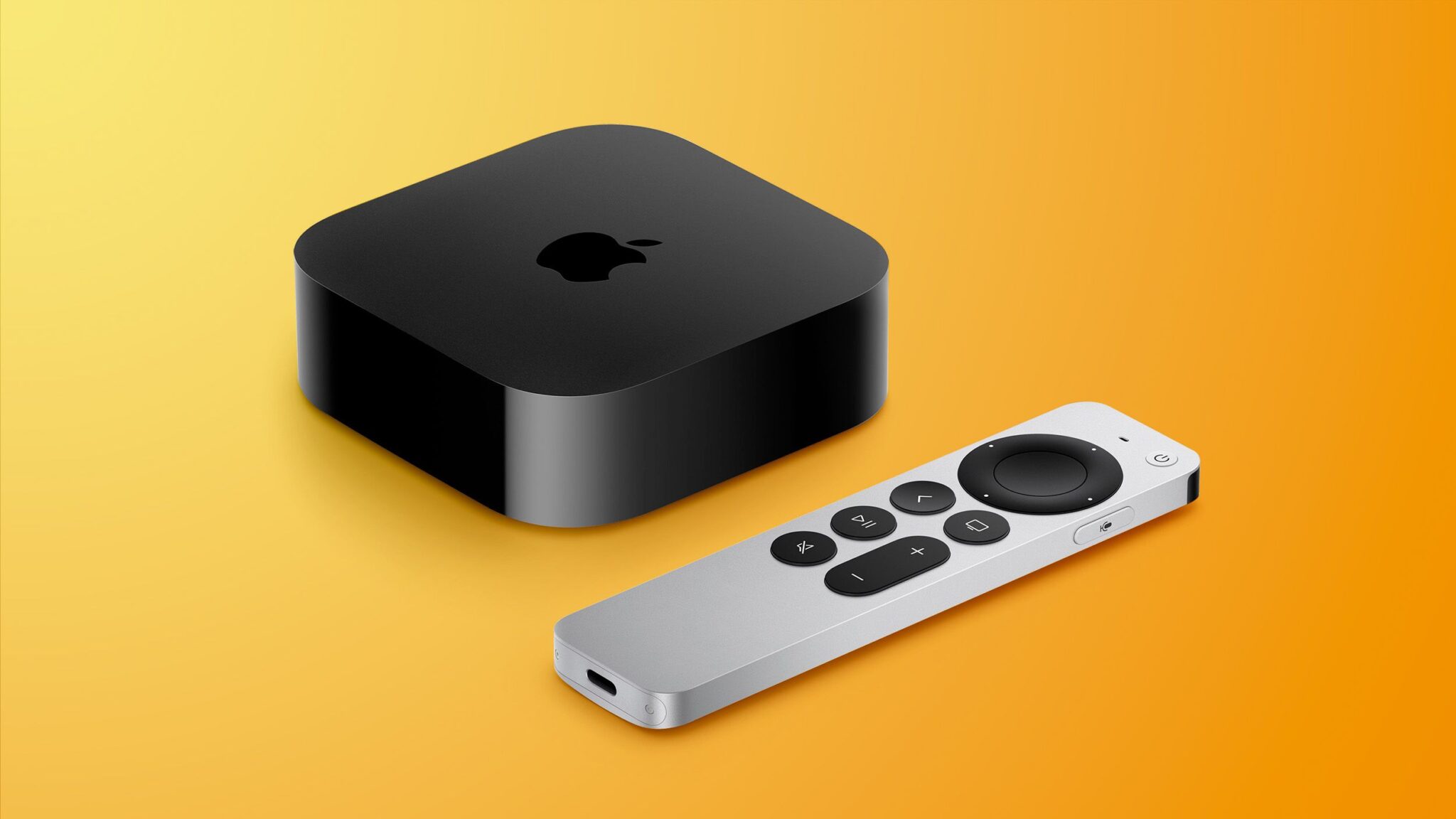 Apple TV 4K black box next to a Siri Remote on a media console under a large TV