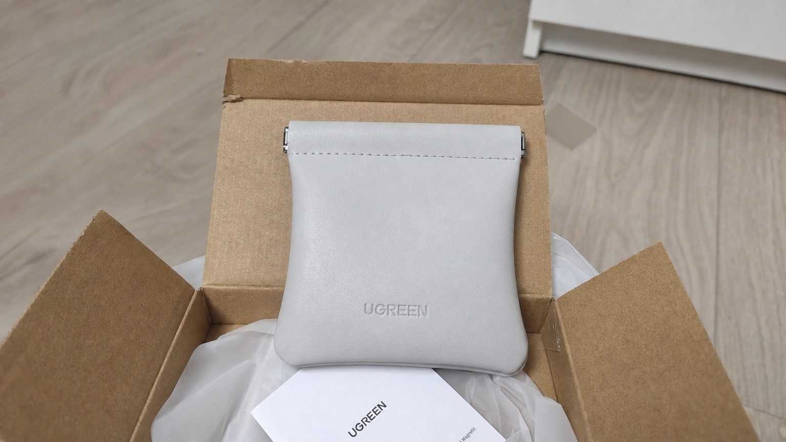 Мешочек для AirPods, который открывается одной рукой. Мешочек Ugreen на фоне коробки. Фото.
