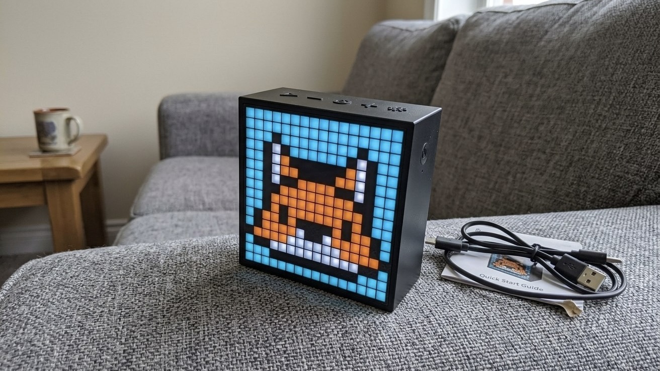 Колонка Divoom Timebox Evo с пиксельной мордочкой лисы на экране стоит на диване