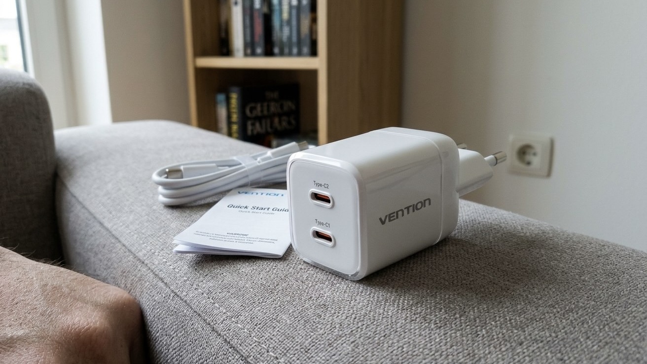 Белый блок питания Vention с двумя портами USB-C стоит на подлокотнике дивана рядом с кабелем и инструкцией