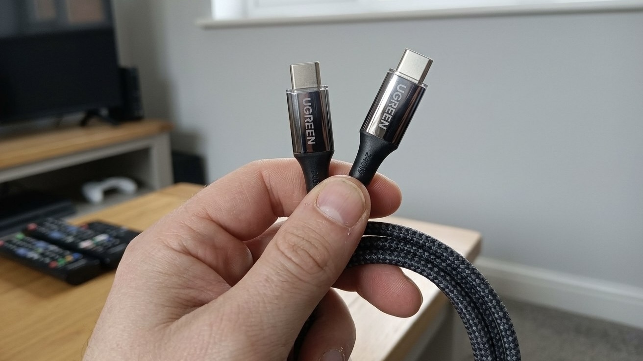 Человек держит в руке кабель UGREEN USB-C в черной оплетке с металлическими коннекторами