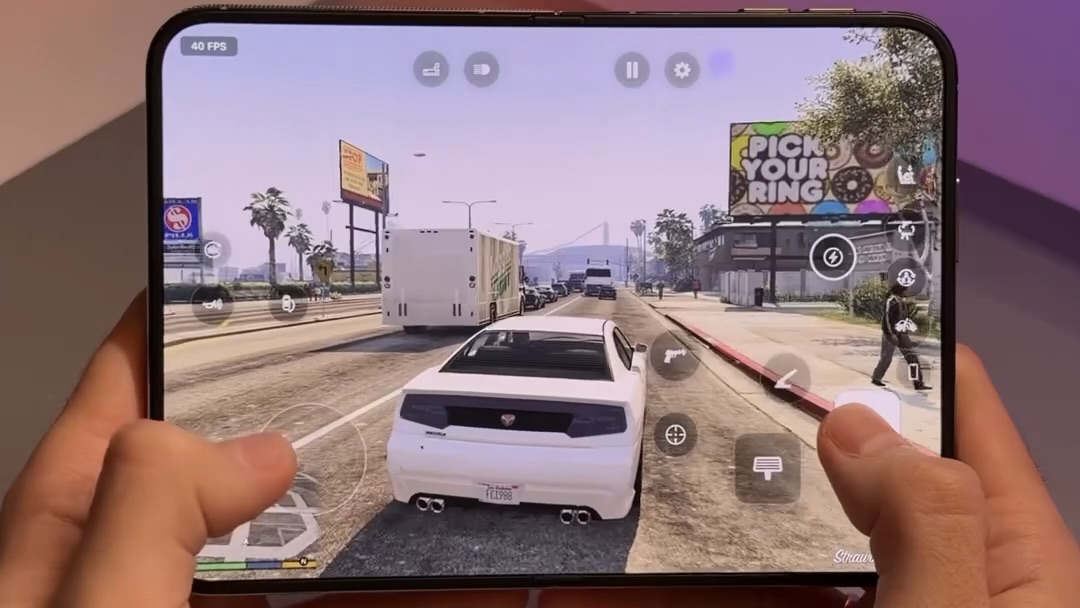 Белый автомобиль едет по шоссе в GTA V на экране складного смартфона. Изображение: BenGeskin