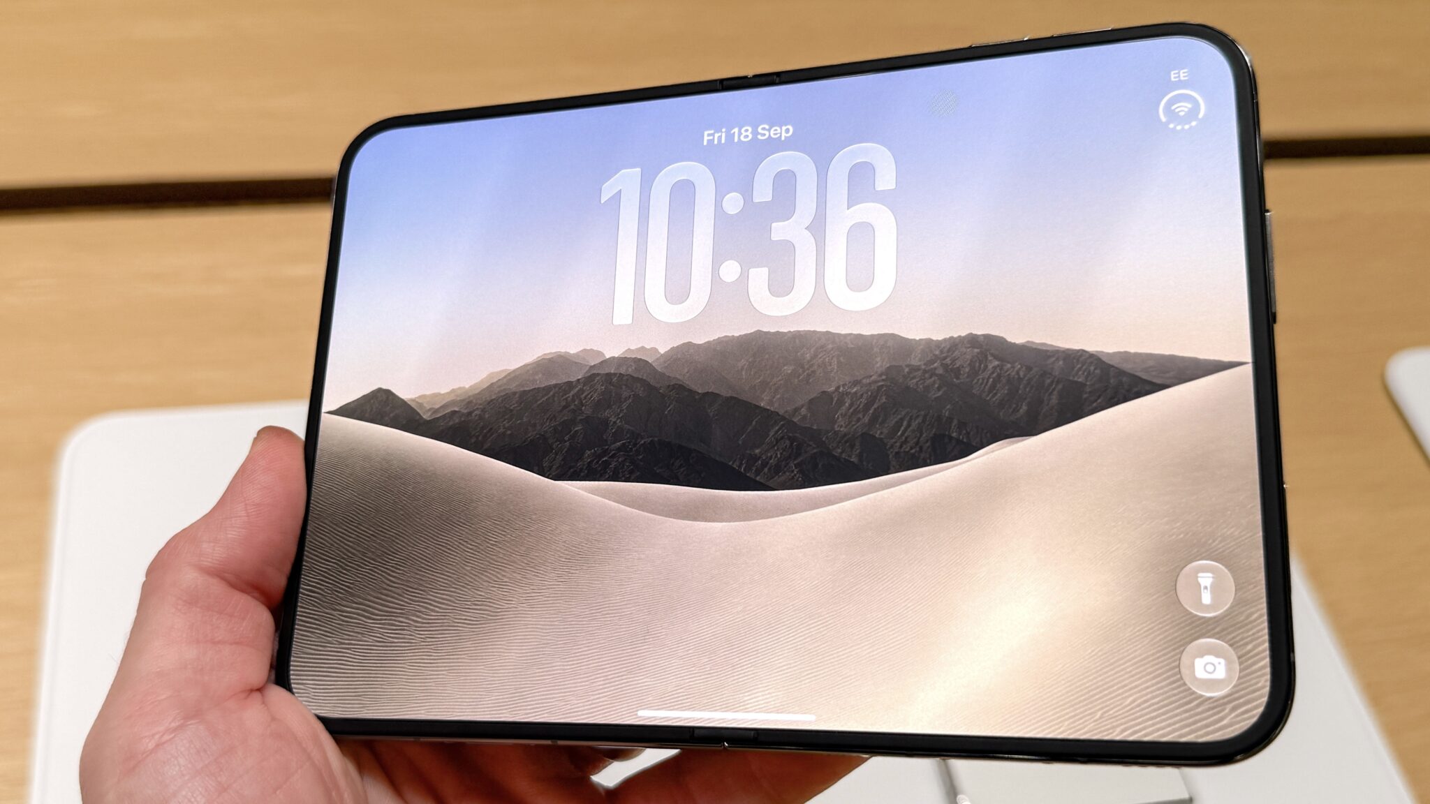 Раскрытый iPhone Duo с экраном блокировки в руке посетителя магазина