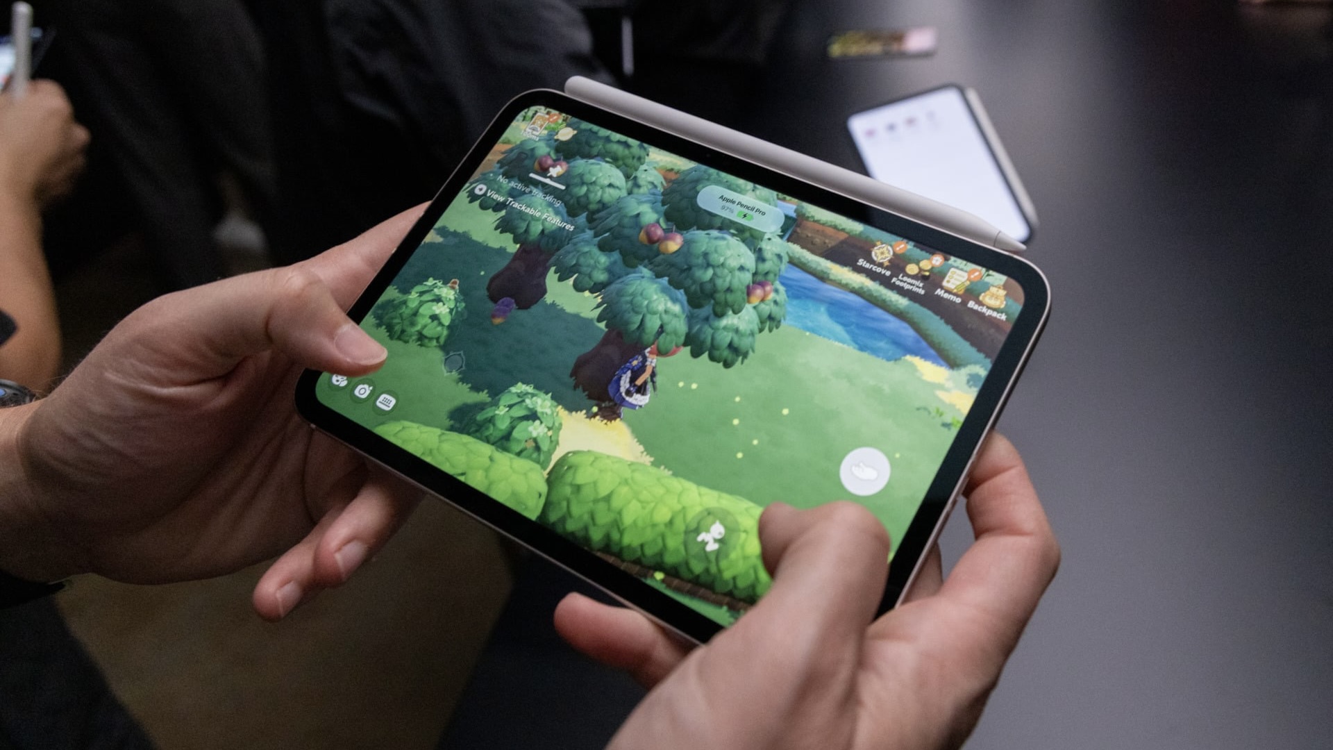 Человек играет в игру на новом iPad mini, сверху к планшету примагничен Apple Pencil Pro