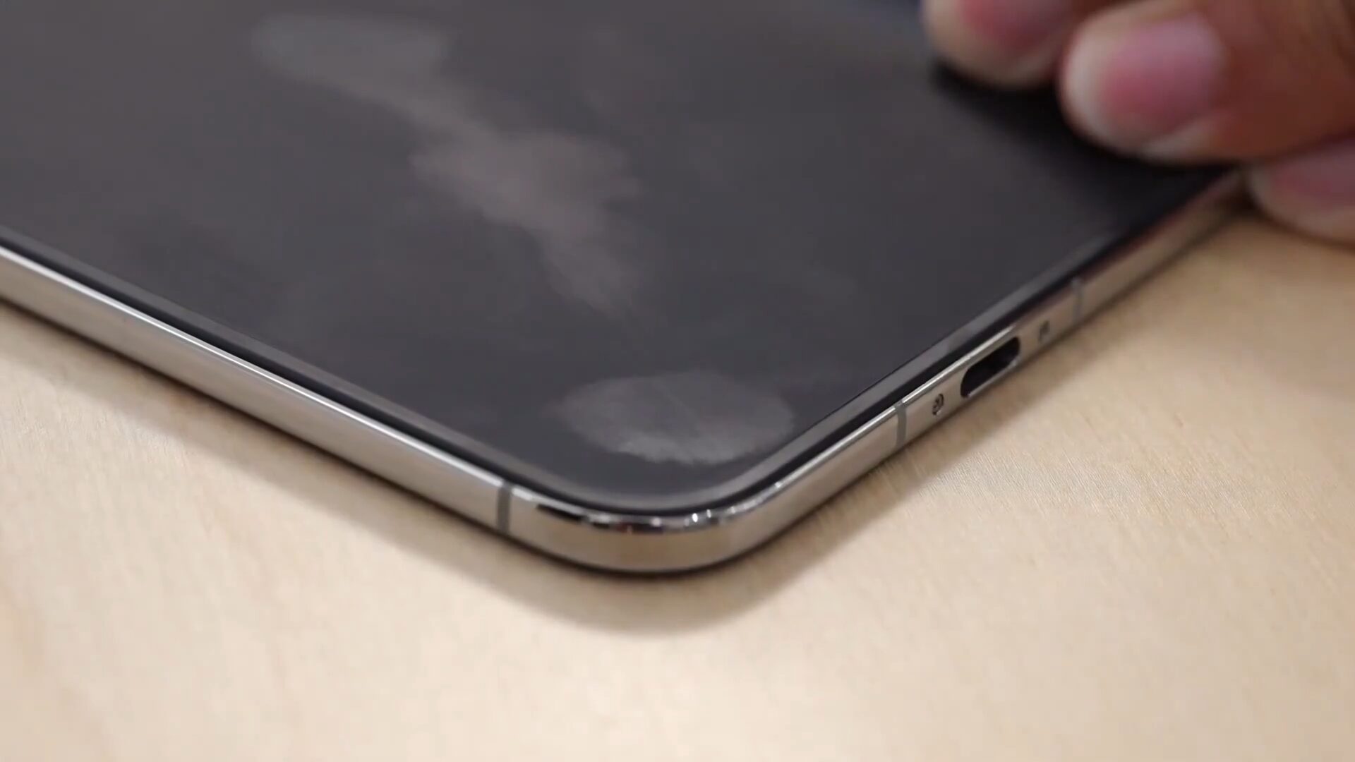Палец оставляет белесые разводы на матовом экране iPhone Duo рядом с портом USB-C