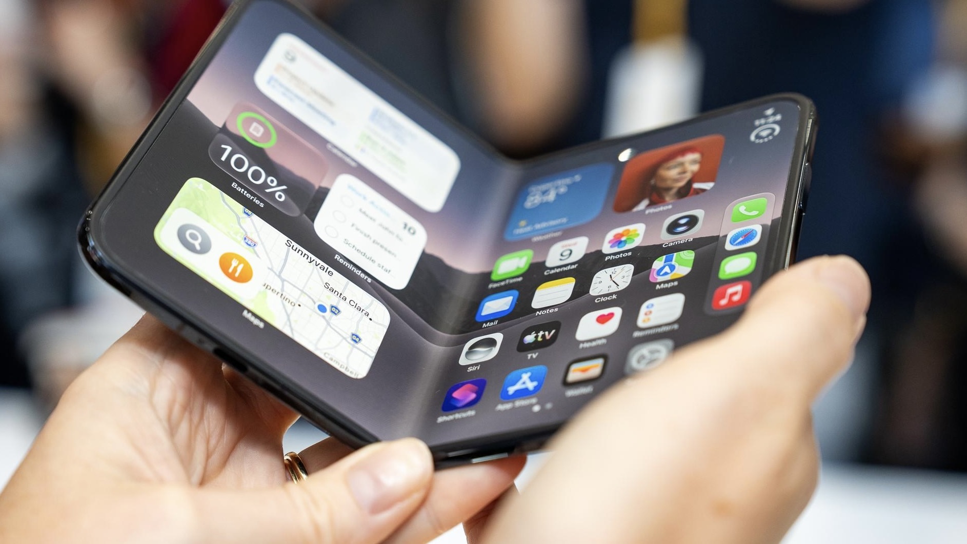 Человек держит в руках наполовину согнутый iPhone Duo с включенным внутренним экраном