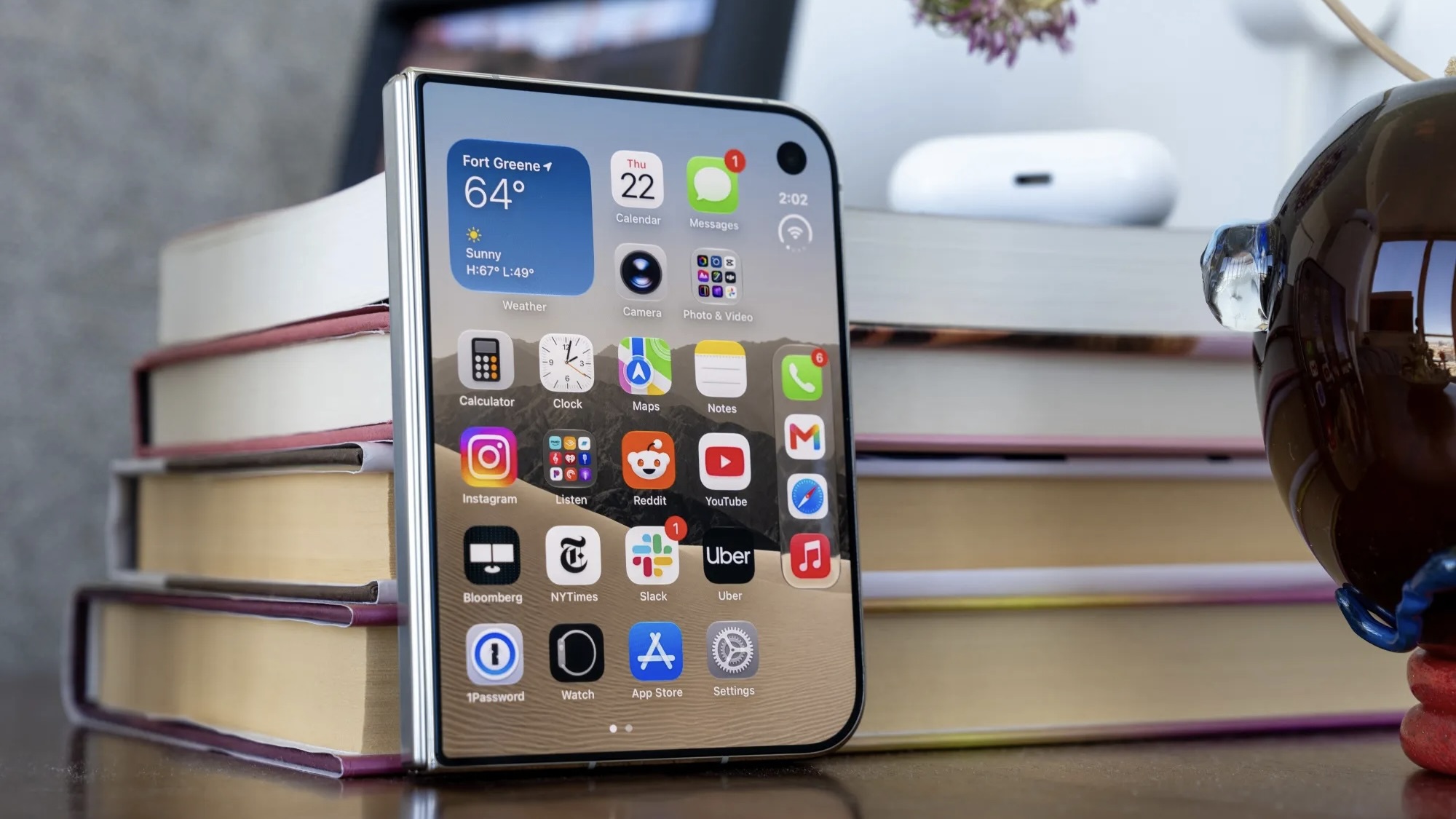 Сложенный iPhone Duo с включенным внешним экраном стоит у стопки книг