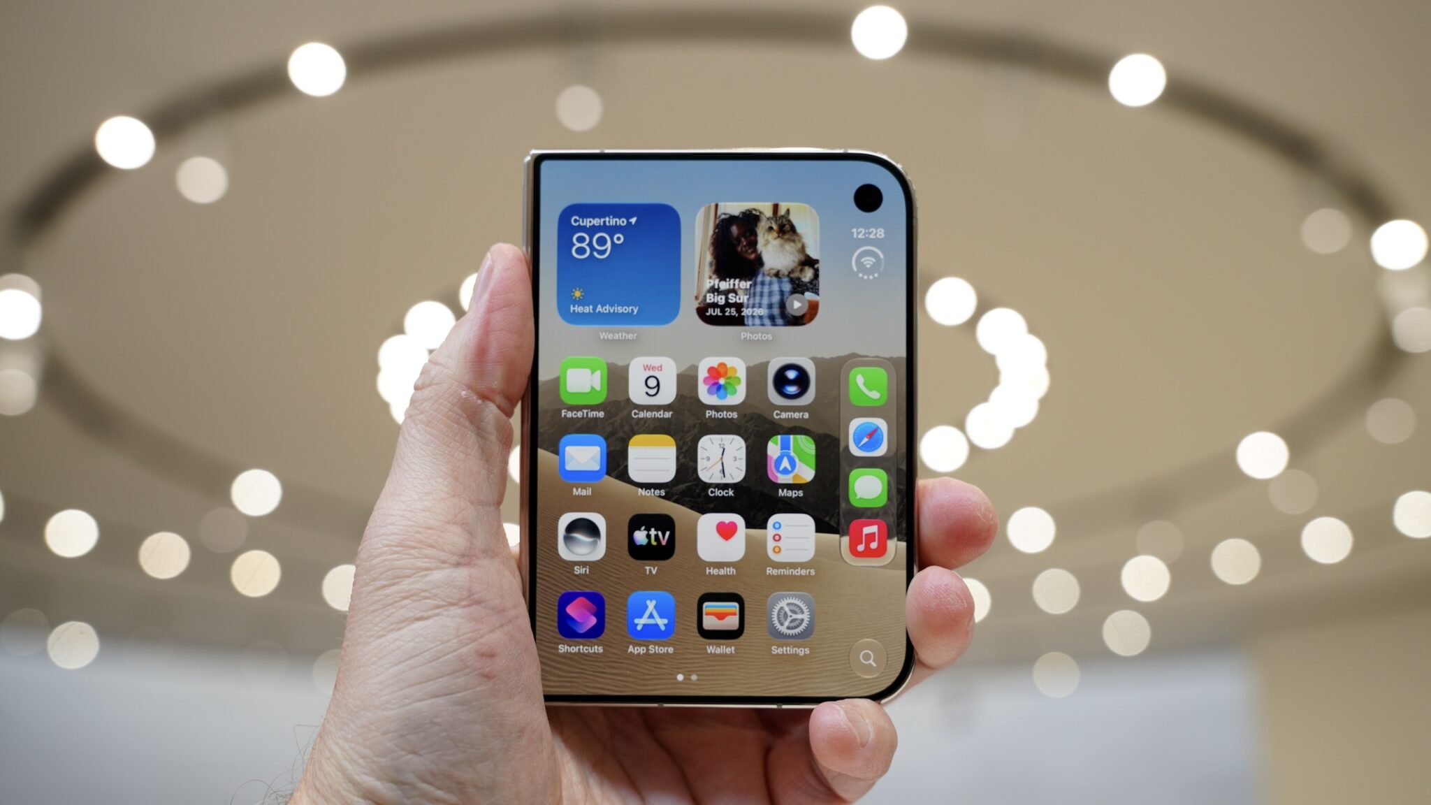 Сложенный iPhone Duo в руке, на внешнем экране открыт рабочий стол с иконками и виджетами