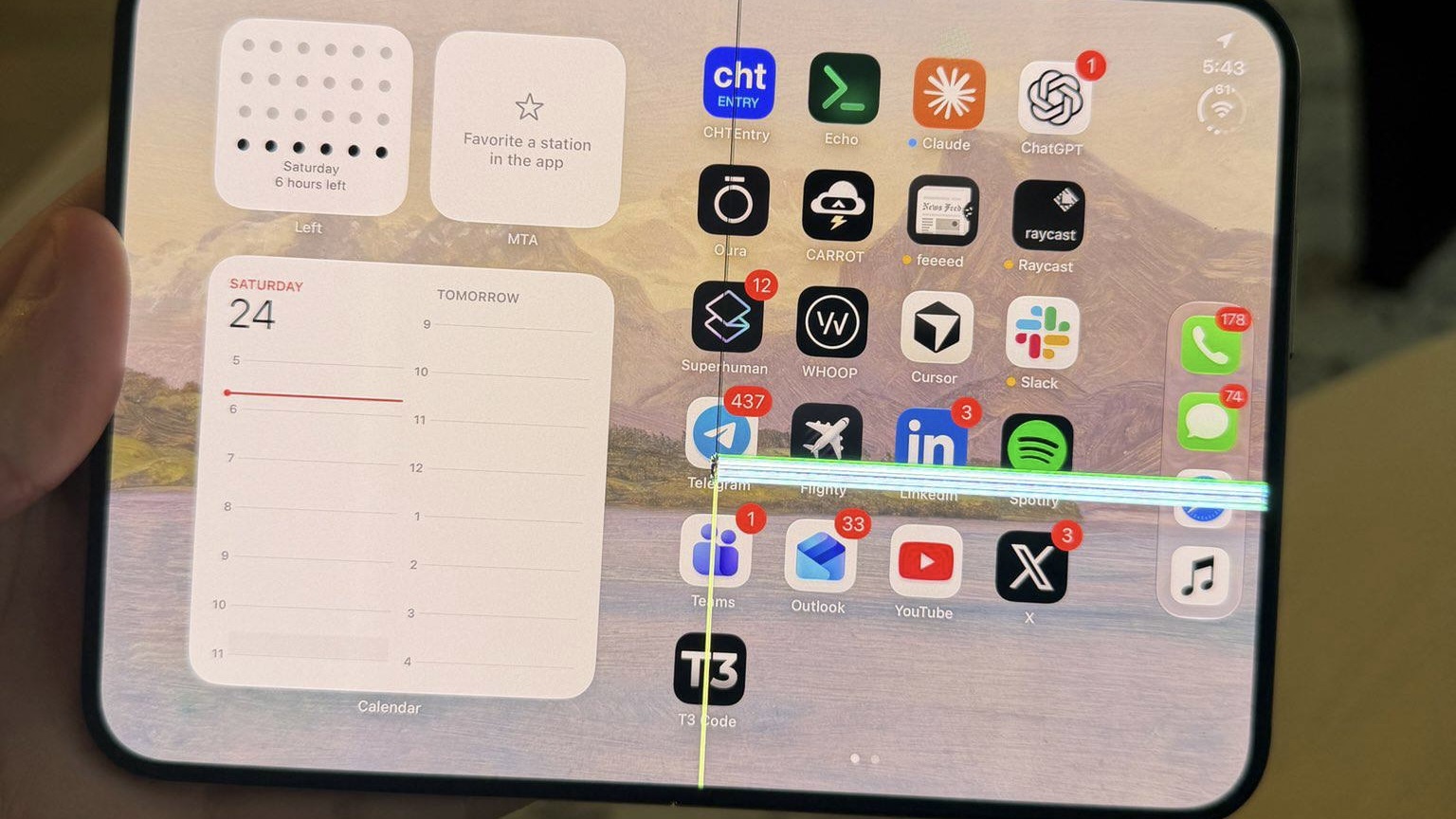 iPhone Duo в руке с трещиной по сгибу и светящейся горизонтальной полосой поперек иконок