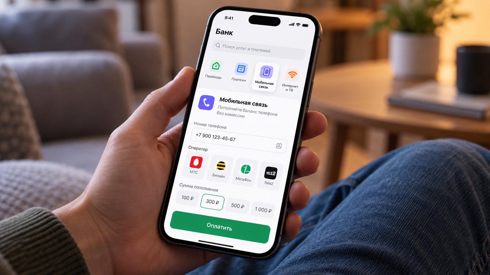 Человек держит iPhone с открытым разделом оплаты мобильной связи в банковском приложении